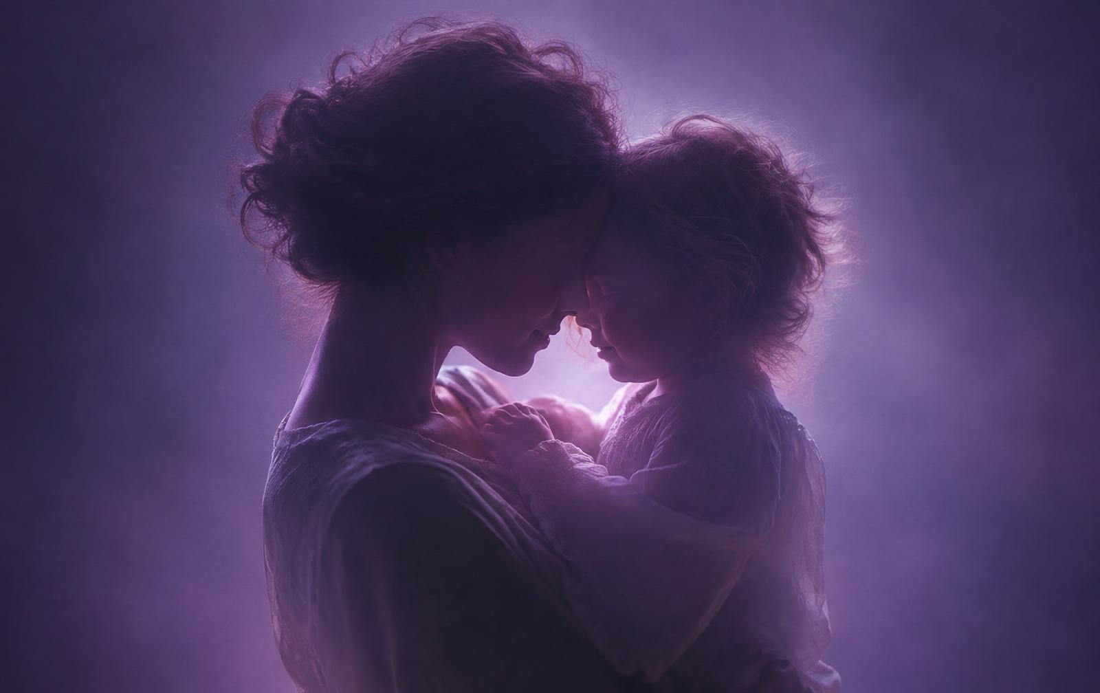 A mother holding her child close in soft violet light — attunement between nurturer and child